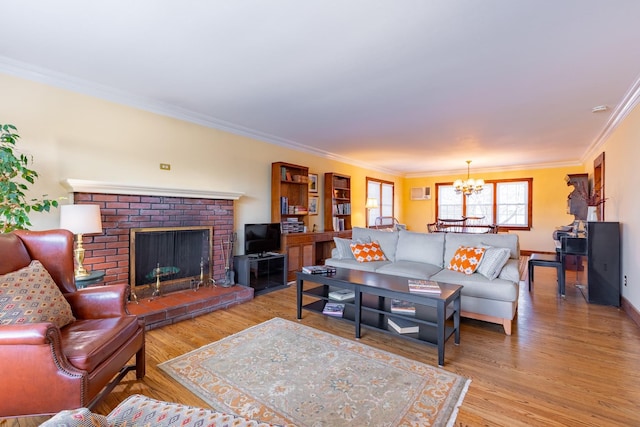 living room with ornamental molding, light hardwood / wood-style floors, a brick fireplace, and a notable chandelier