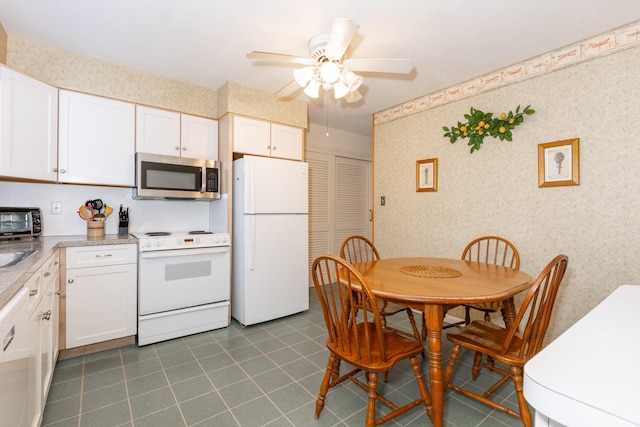 kitchen with white cabinetry, dark tile patterned flooring, white appliances, and ceiling fan