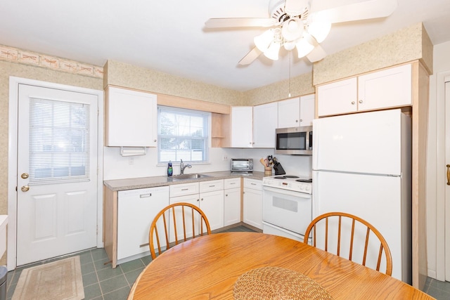 kitchen featuring sink, white appliances, dark tile patterned floors, ceiling fan, and white cabinets