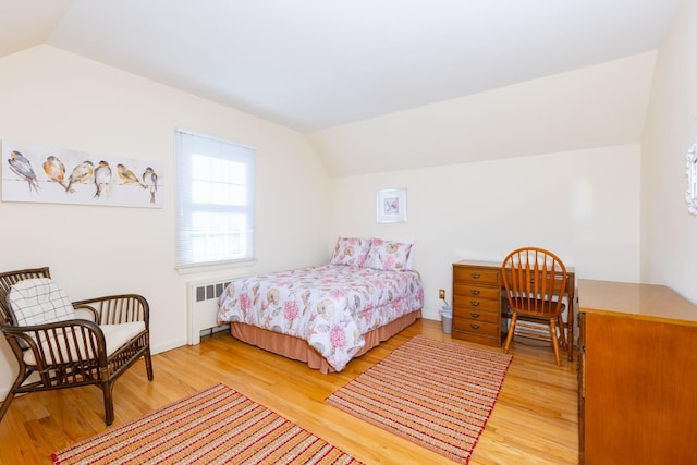 bedroom with lofted ceiling, hardwood / wood-style floors, and radiator heating unit