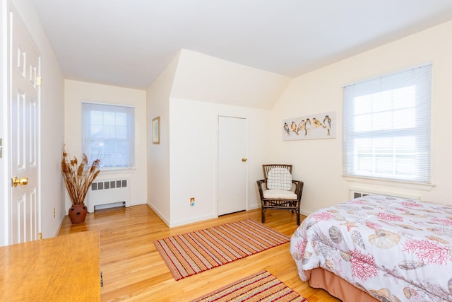 bedroom featuring vaulted ceiling, radiator, and hardwood / wood-style floors