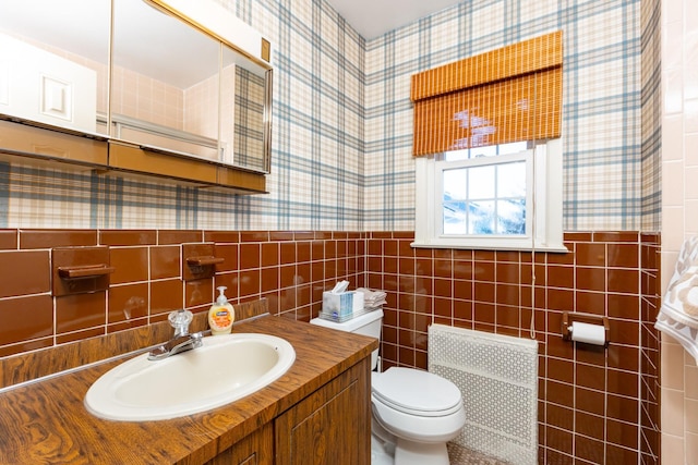 bathroom featuring vanity, tile walls, and toilet