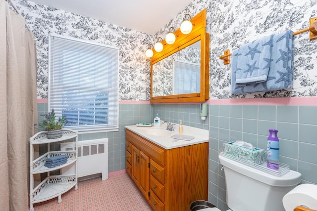 bathroom with radiator, tile walls, vanity, toilet, and tile patterned floors