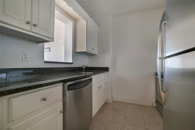 kitchen with light tile patterned flooring, sink, fridge, stainless steel dishwasher, and white cabinets