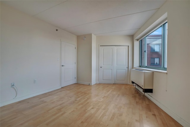 unfurnished bedroom featuring radiator, light hardwood / wood-style flooring, and a closet