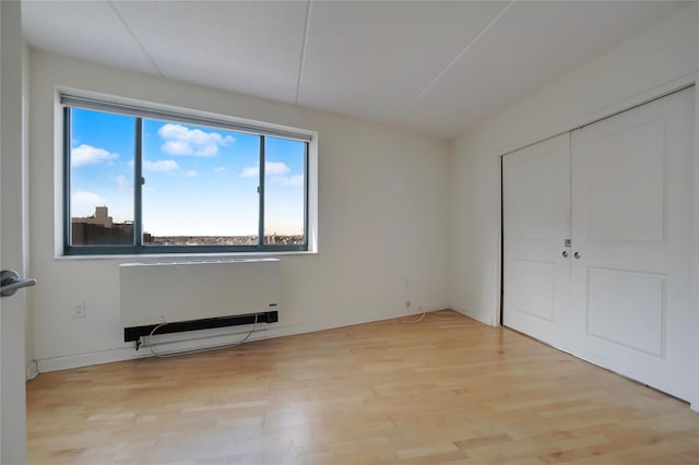 unfurnished bedroom with radiator, light hardwood / wood-style floors, and a closet