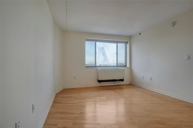 empty room with heating unit and light wood-type flooring