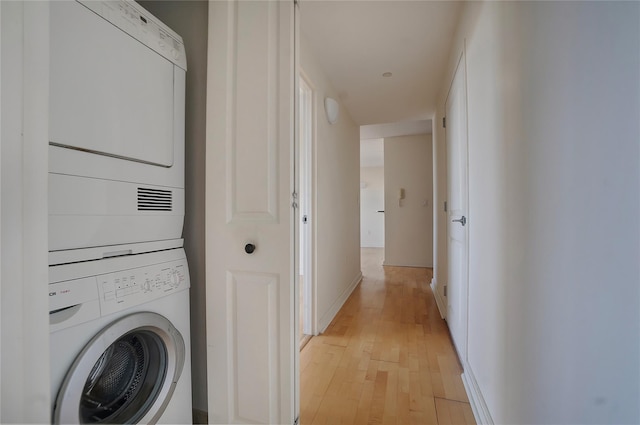 laundry area featuring stacked washing maching and dryer and light wood-type flooring