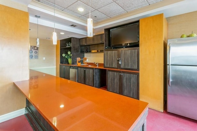 kitchen featuring pendant lighting, sink, stainless steel appliances, dark brown cabinetry, and kitchen peninsula