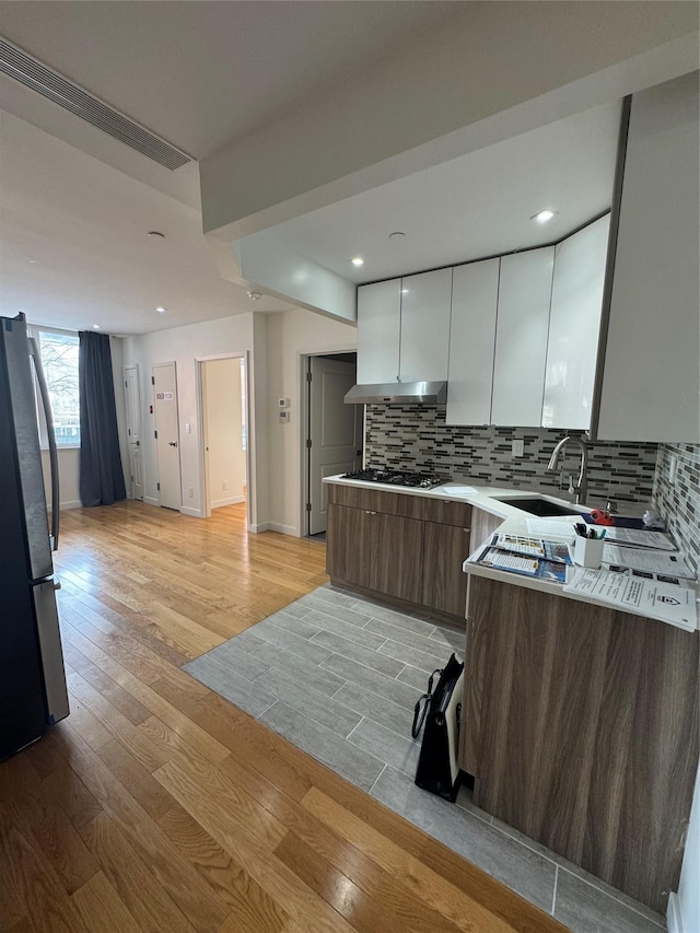 kitchen featuring appliances with stainless steel finishes, light wood-type flooring, a sink, and modern cabinets