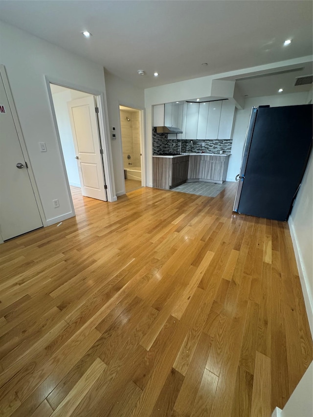 kitchen with visible vents, backsplash, light wood-style flooring, freestanding refrigerator, and modern cabinets