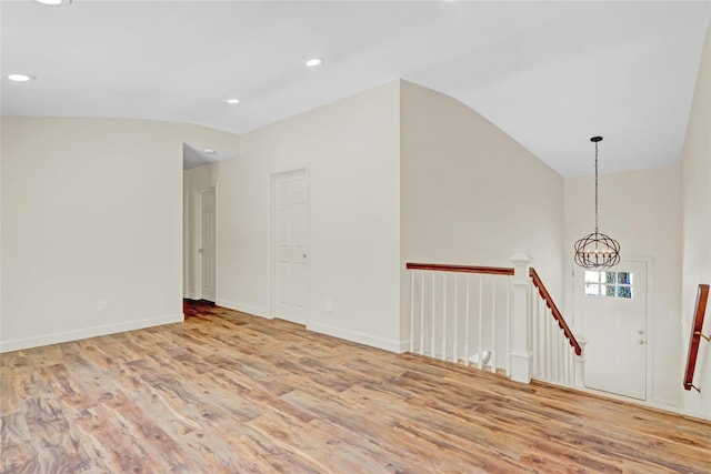 unfurnished room with vaulted ceiling, a chandelier, and light hardwood / wood-style flooring