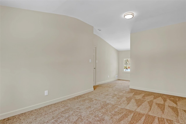 empty room with light colored carpet and lofted ceiling