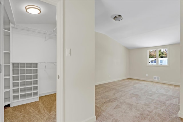 interior space with vaulted ceiling and light colored carpet