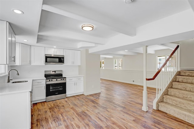 kitchen featuring sink, white cabinets, stainless steel appliances, beam ceiling, and light hardwood / wood-style flooring