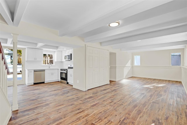 kitchen with white cabinetry, beam ceiling, stainless steel appliances, and light wood-type flooring