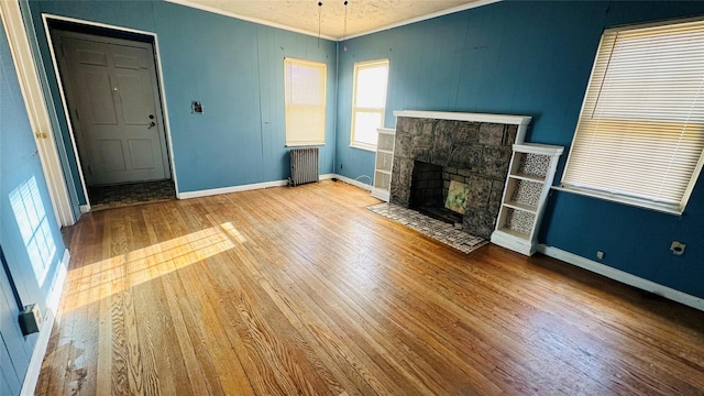 unfurnished living room with ornamental molding, radiator, a fireplace, and light hardwood / wood-style flooring