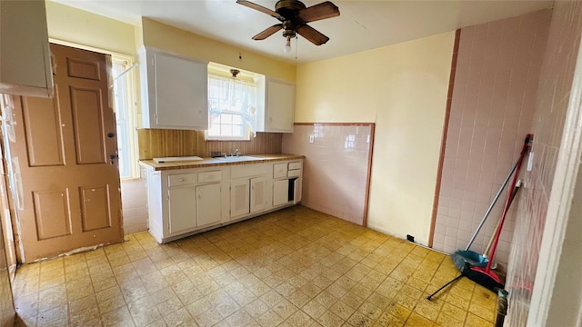 kitchen with sink, tile walls, white cabinets, and ceiling fan