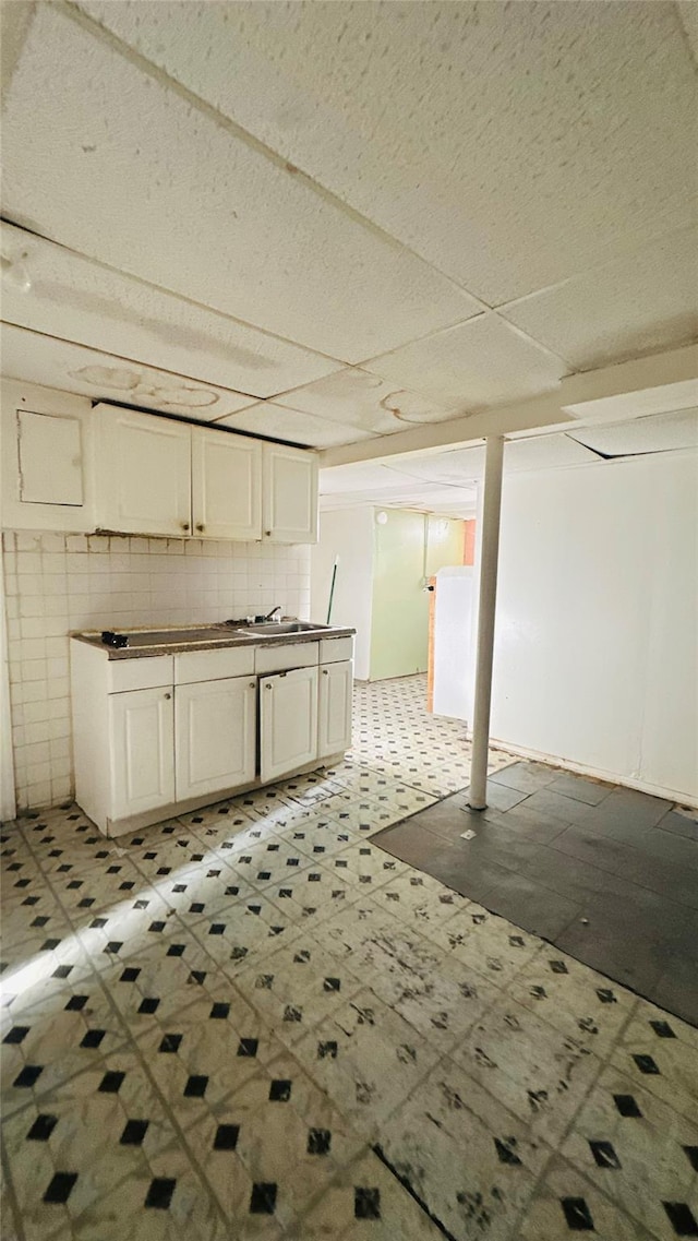 basement featuring a paneled ceiling and sink