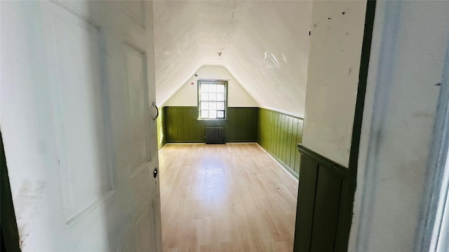 bonus room with lofted ceiling, radiator heating unit, and light hardwood / wood-style flooring