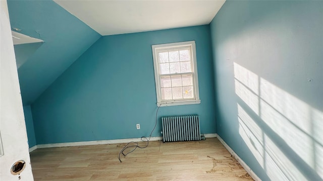 additional living space with lofted ceiling, radiator heating unit, and light hardwood / wood-style flooring