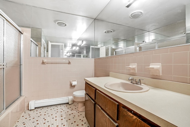 full bathroom featuring tile walls, enclosed tub / shower combo, vanity, baseboard heating, and toilet