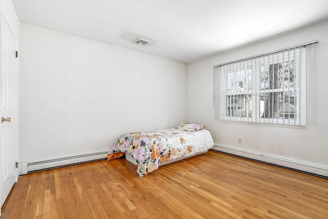 unfurnished bedroom featuring a baseboard heating unit and light hardwood / wood-style flooring