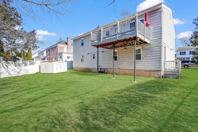 back of property featuring a wooden deck, a yard, and a storage unit