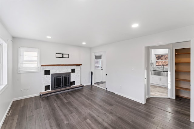 unfurnished living room featuring sink, a fireplace, and dark hardwood / wood-style floors