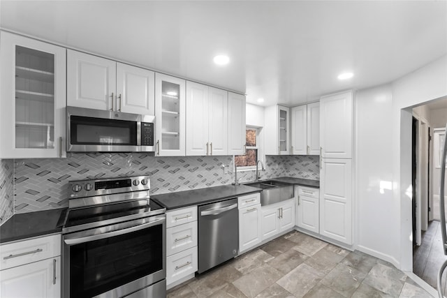 kitchen with white cabinetry, appliances with stainless steel finishes, sink, and backsplash