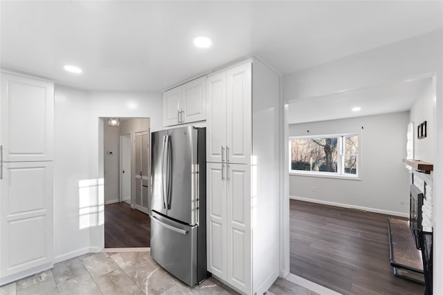 kitchen with white cabinetry, stainless steel fridge, and light hardwood / wood-style floors