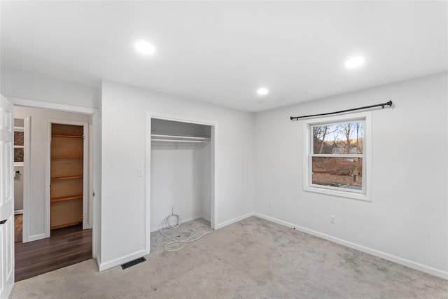 unfurnished bedroom with light colored carpet and a closet