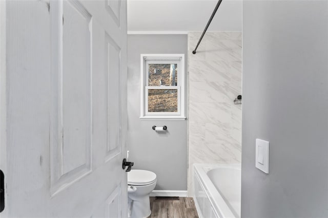 bathroom with wood-type flooring, bathing tub / shower combination, and toilet