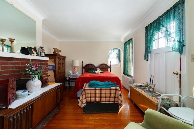 bedroom featuring dark hardwood / wood-style flooring, radiator, and ornamental molding