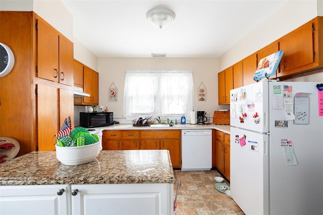 kitchen with light stone counters, white appliances, and sink