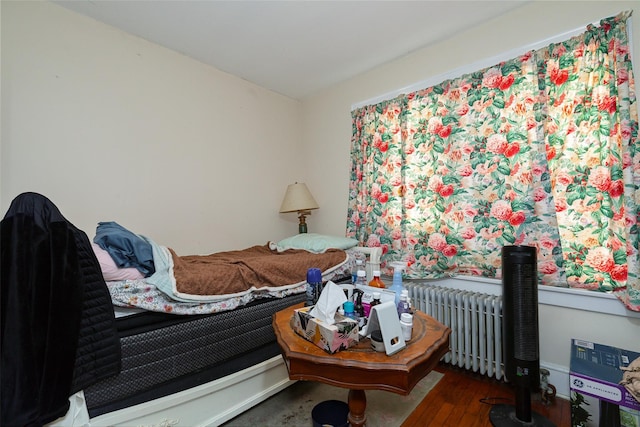 bedroom with dark wood-type flooring and radiator heating unit