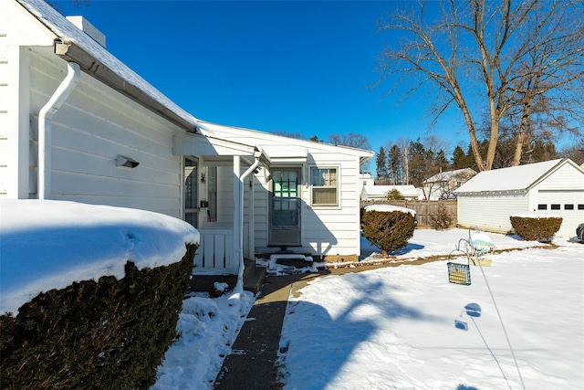 view of snowy exterior with a garage and an outbuilding