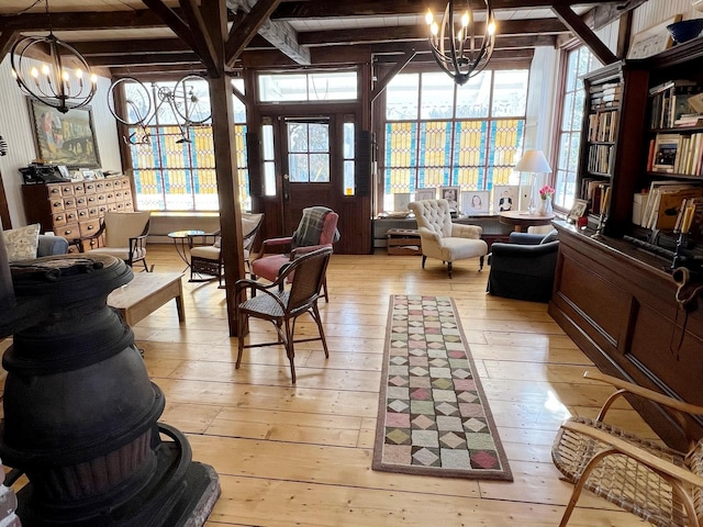 living area featuring an inviting chandelier, light hardwood / wood-style flooring, and beamed ceiling