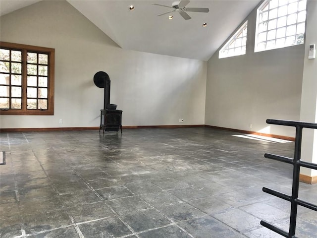 unfurnished living room featuring ceiling fan, high vaulted ceiling, and a wood stove