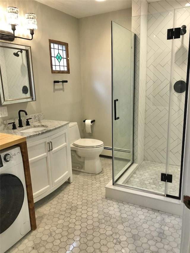 bathroom featuring washer / dryer, vanity, walk in shower, baseboard heating, and toilet