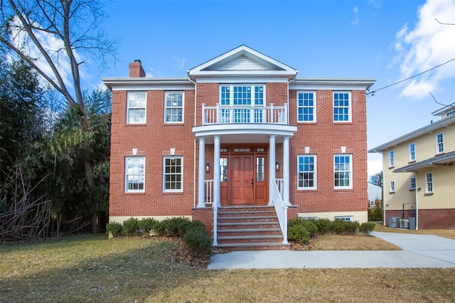 view of front of home featuring a balcony, a front yard, and central air condition unit