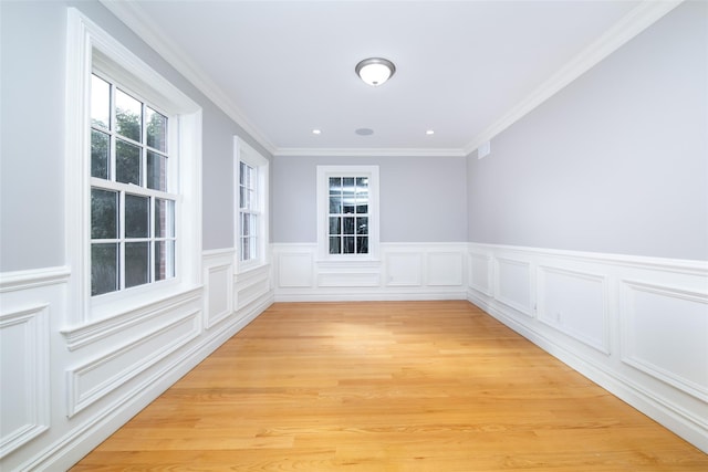 spare room with ornamental molding, light wood-type flooring, a wainscoted wall, and recessed lighting