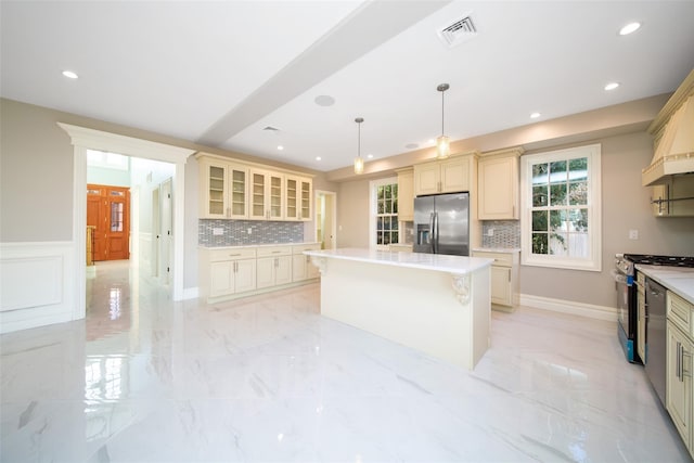 kitchen featuring light countertops, appliances with stainless steel finishes, hanging light fixtures, and a kitchen island