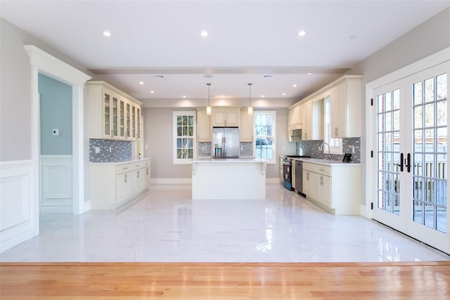 kitchen with glass insert cabinets, a center island, french doors, and decorative light fixtures