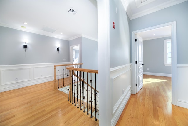 corridor with ornamental molding, visible vents, light wood finished floors, and an upstairs landing