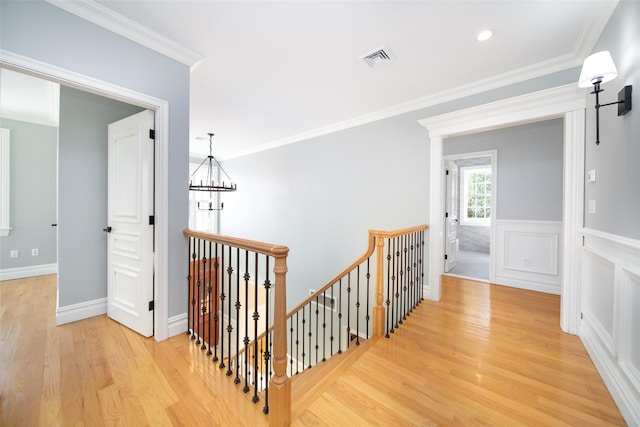 hall featuring crown molding, a notable chandelier, visible vents, an upstairs landing, and light wood-type flooring