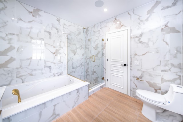 full bath featuring toilet, a garden tub, a marble finish shower, and tile walls