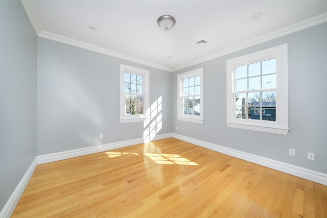 empty room with baseboards, light wood-style flooring, visible vents, and crown molding