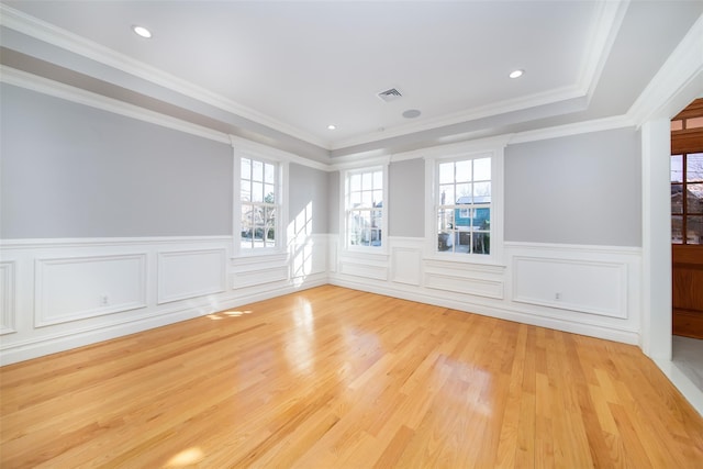 unfurnished room featuring light wood-style flooring, visible vents, crown molding, and wainscoting