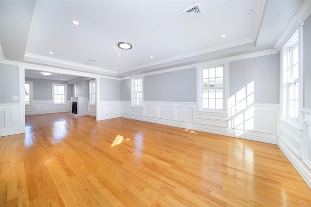 unfurnished living room featuring light wood-type flooring, a fireplace, a raised ceiling, and visible vents